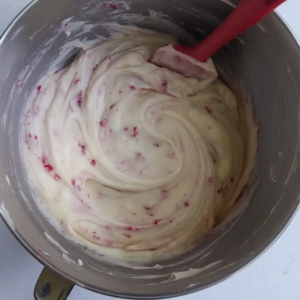 Raspberry cupcake batter with raspberries in paper liners ready for baking.