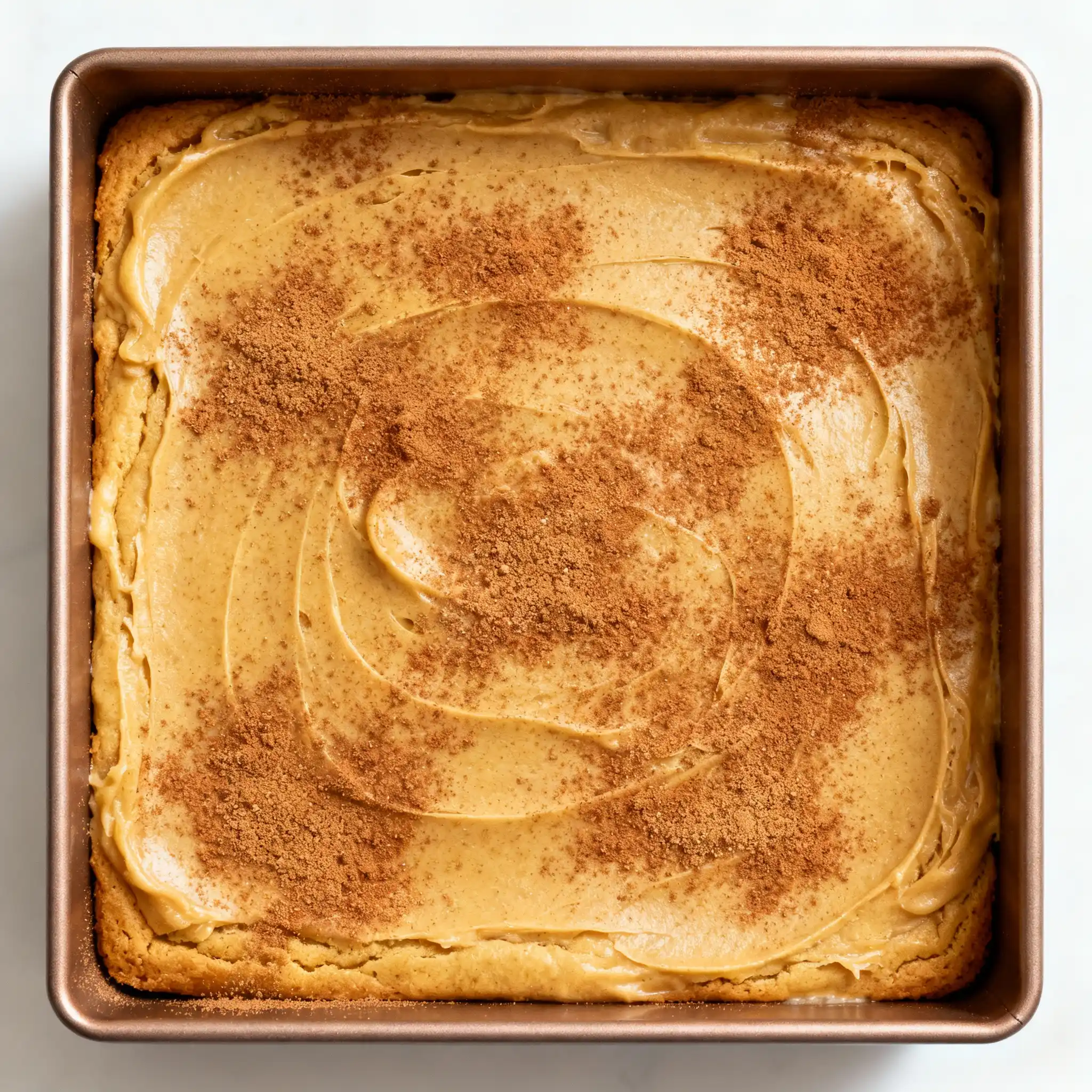 Sprinkling cinnamon sugar over Pumpkin Snickerdoodle Blondie batter before baking.