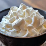 Homemade dairy free whipping cream in a glass bowl with soft peaks