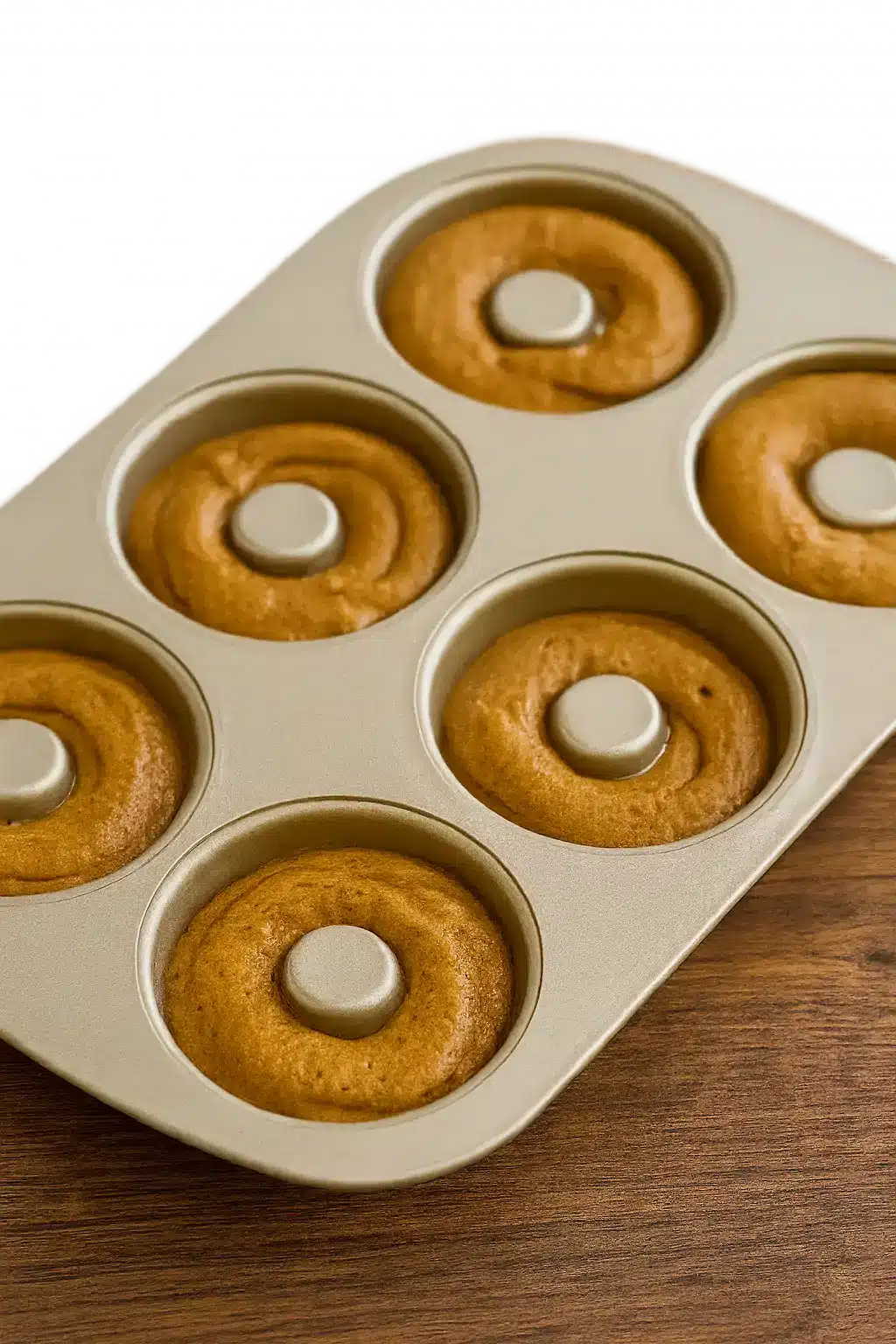 Pouring vegan gingerbread chai donut batter into a donut pan.